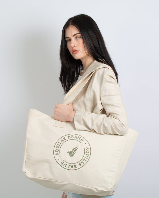 A stylish woman confidently holds a chic canvas tote bag with a green embroidered logo, adding a touch of eco-friendly fashion to her ensemble.